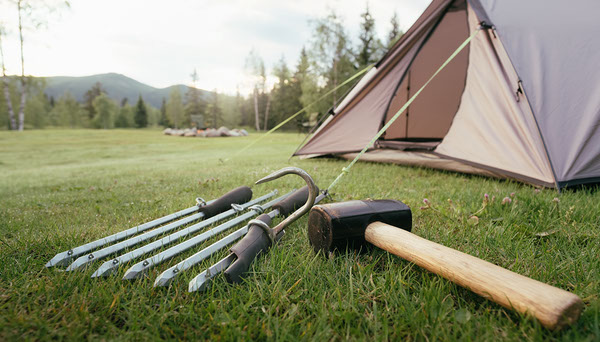 Tent Stake Mallet vs Rock: What Should Campers Use? Tent stakes, stake puller and camping mallet laid near a tent